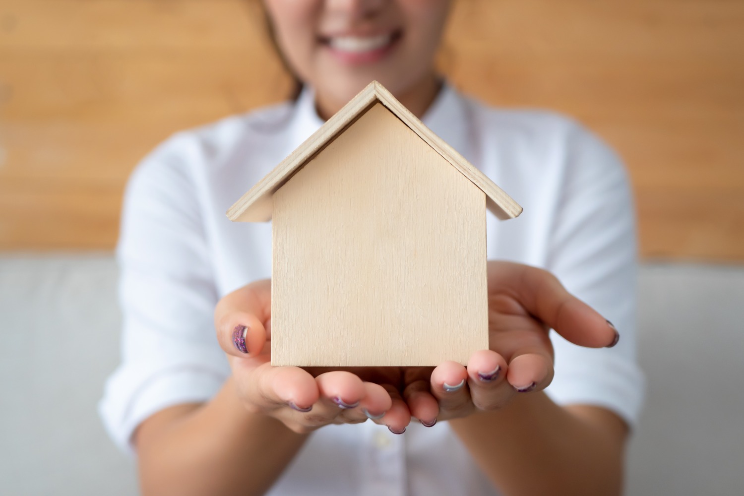 Woman holding small wooden house in hands - home buying